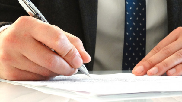 Main d'un homme, en train de signer un contrat d'assurance